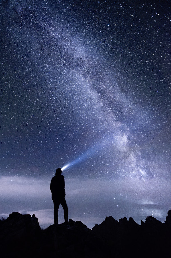 Man with headtorch under starry sky